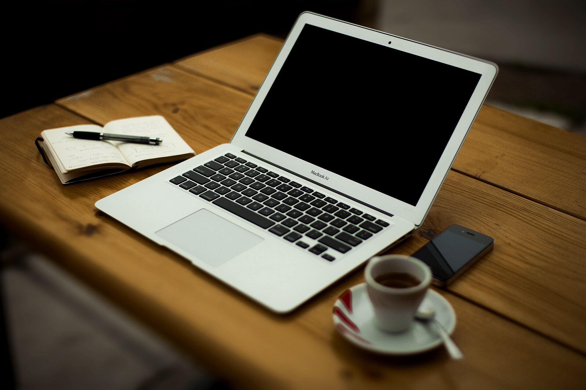 A laptop and a cup of coffee on a wooden desk at home